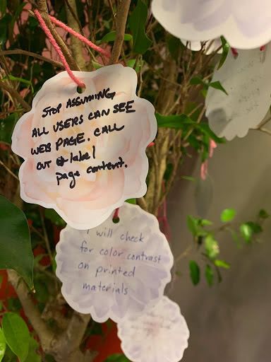 Several reflections written on paper flowers and hung from a branch on the tree.